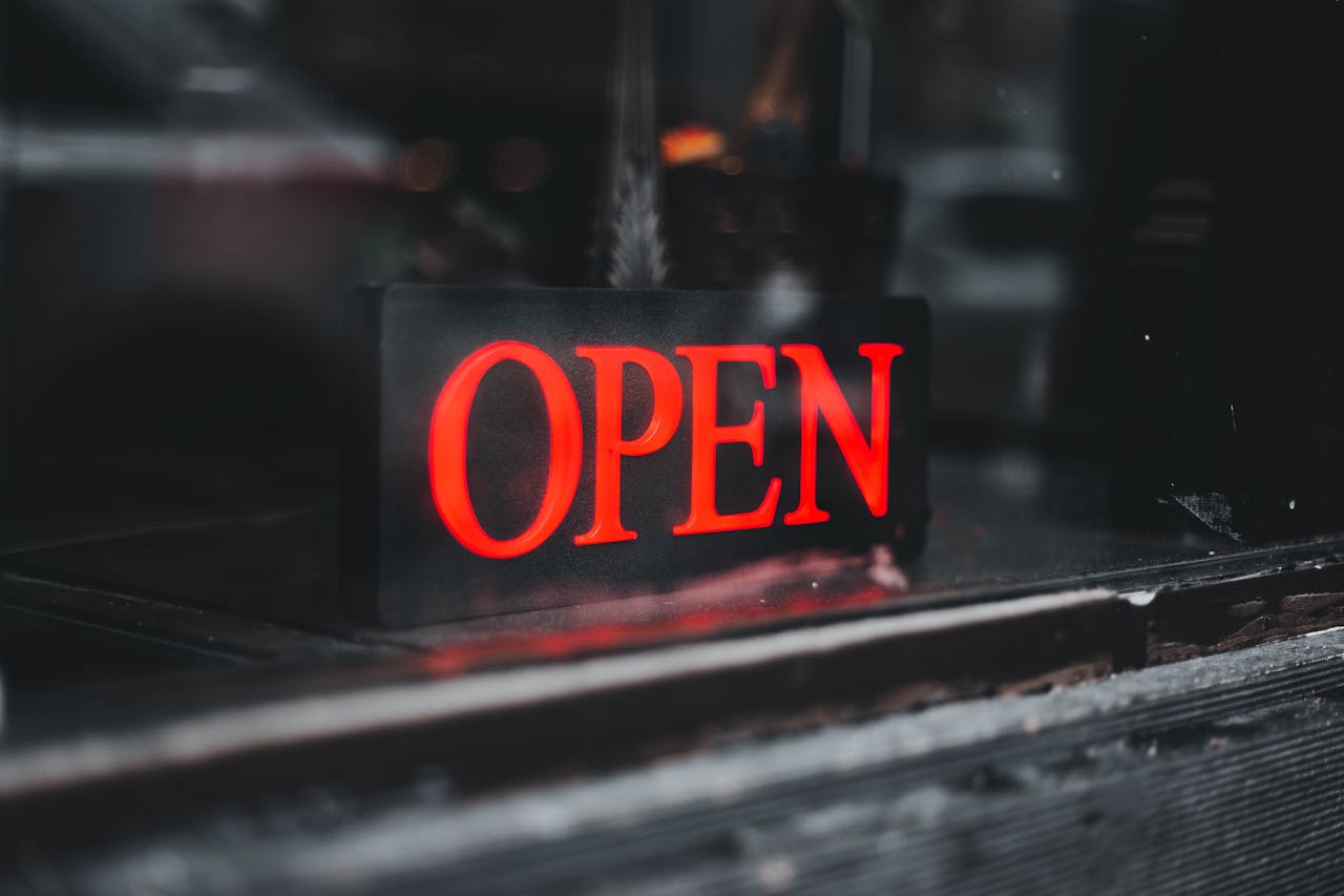 Vibrant red neon open sign in a storefront window, inviting customers.