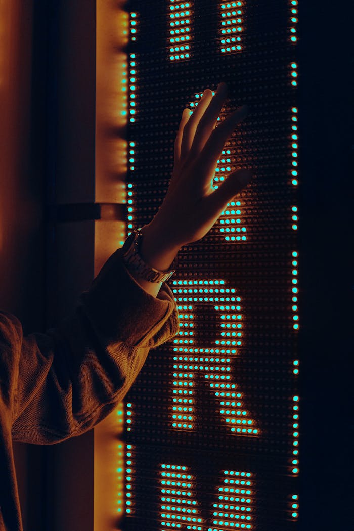 A hand reaching towards a brightly lit neon sign in the dark with a warm glow.