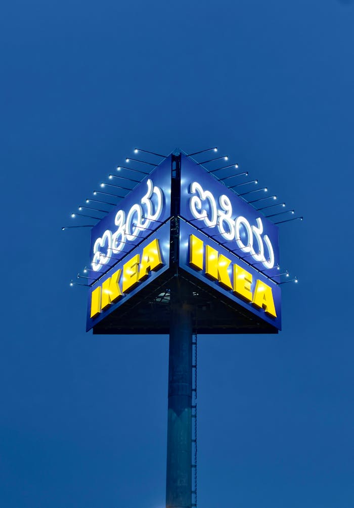 A glowing IKEA sign stands tall against a clear night sky, illuminating the surroundings.
