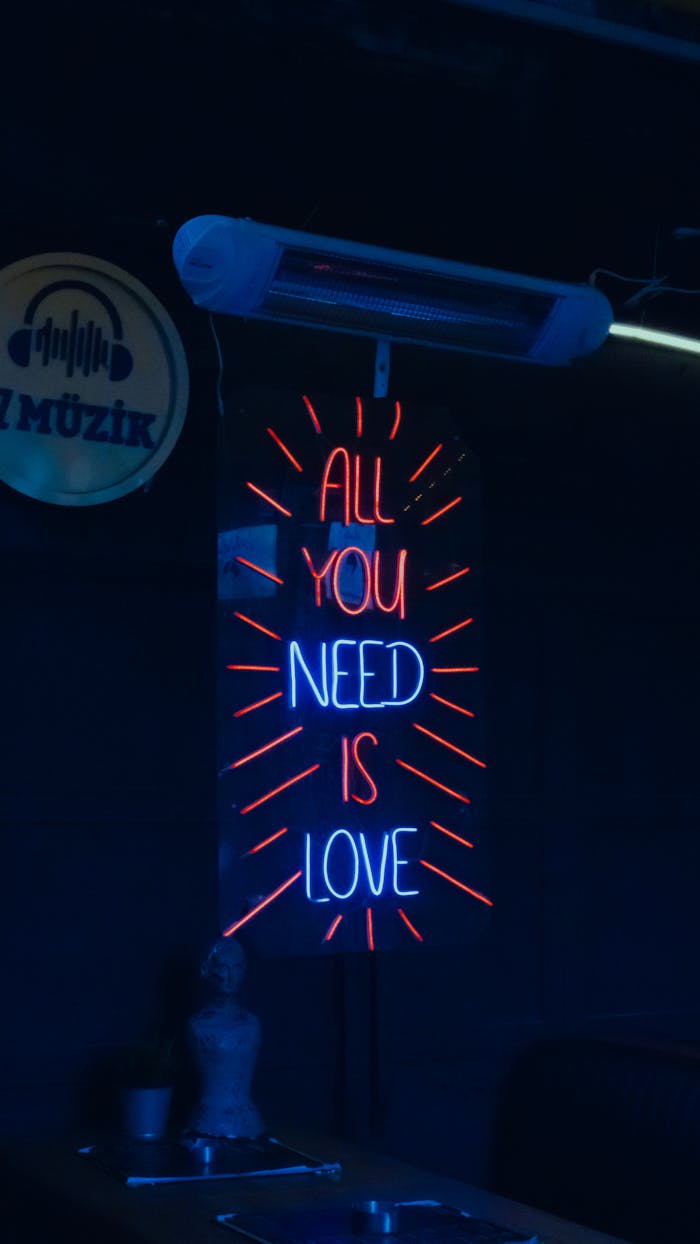 Vibrant neon sign 'All You Need Is Love' in a dimly lit Istanbul venue, conveying a nostalgic atmosphere.